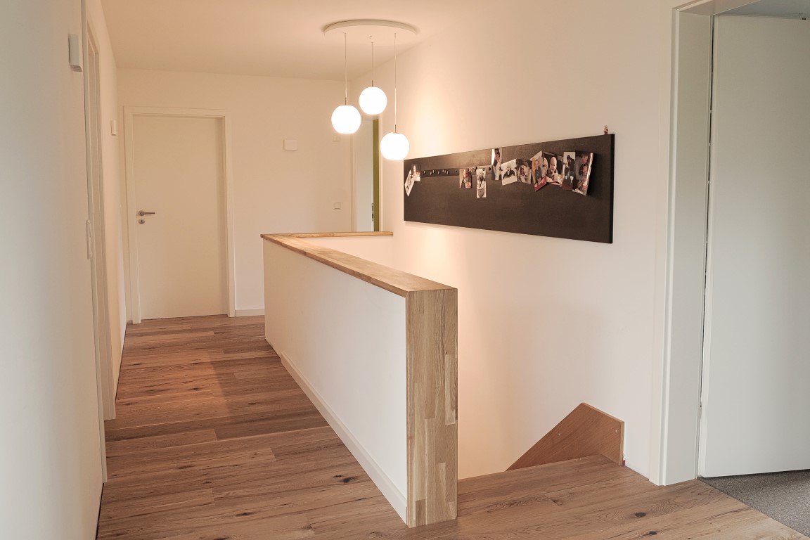 Heller Flur mit Holzbrüstung und Dielenboden nach dem Innenausbau