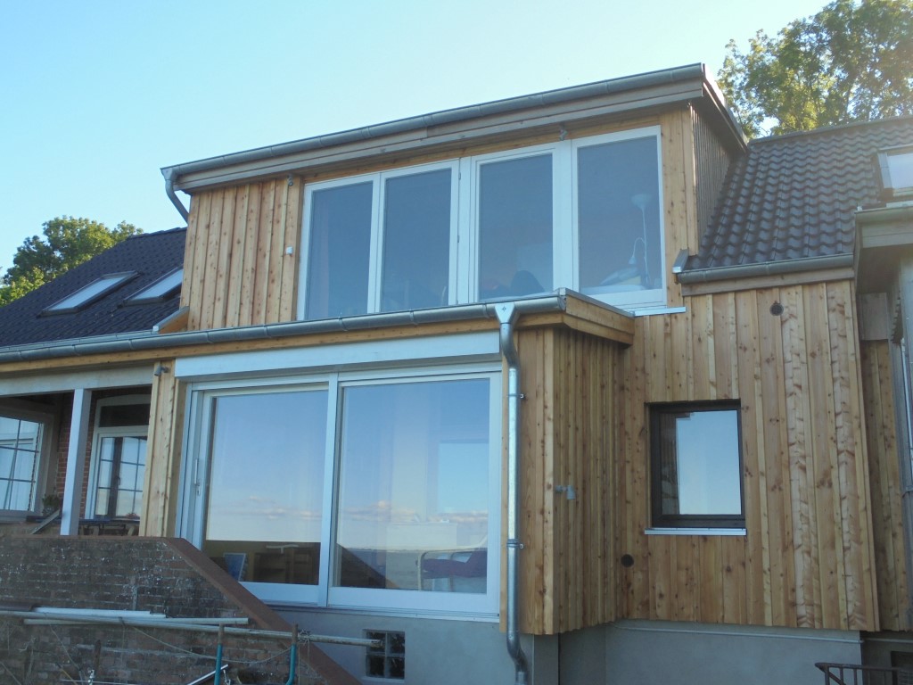 Zweigeschossiger Anbau mit senkrechter Holzschalung und großen Fenstern
