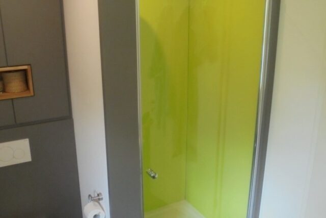 Bad mit bodengleicher Dusche und grüner Glaswand
